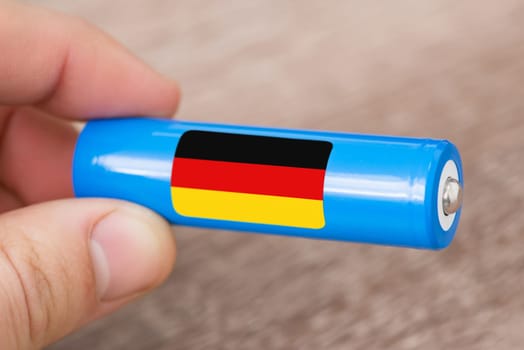 Rechargeable battery with flag of Germany in hand of a man