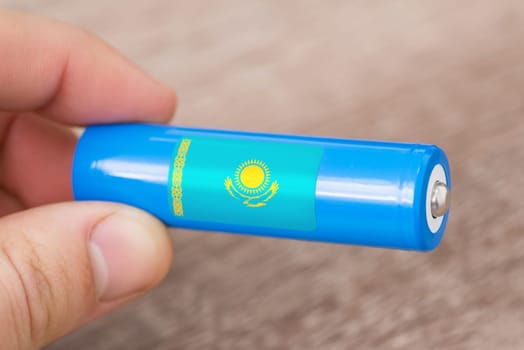 Rechargeable li-ion battery in hand of a man with sticker of Kazakhstan flag