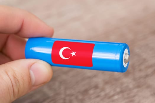 Rechargeable li-ion battery in hand of a man with sticker of Turkey flag