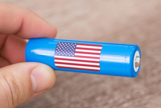 Rechargeable li-ion battery in hand of a man with sticker of USA flag