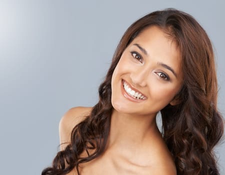 Portrait, beauty and hair of happy woman in makeup in studio isolated on a grey background. Face, smile or curly hairstyle of model in cosmetics, hairdresser and salon treatment for care of skin glow.