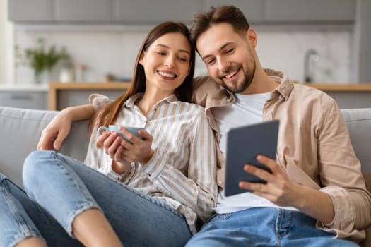 Young couple relaxing at home with coffee and tablet