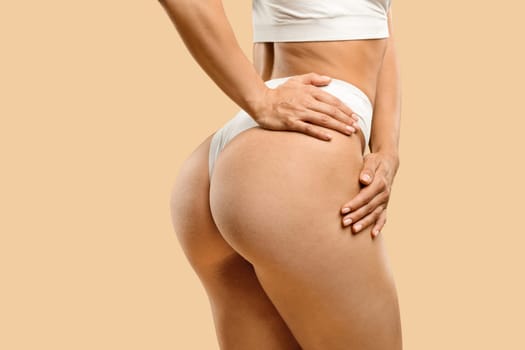 Unrecognizable young fit woman in white underwear showing smooth skin on buttocks
