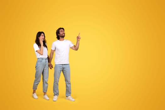 Joyful woman and man in casual white tops and blue jeans holding hands
