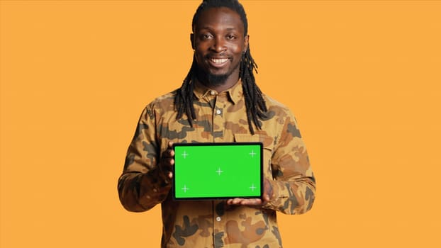 Male model holding laptop with greenscreen layout in studio