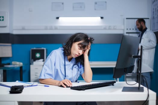 Tired nurse using desktop computer