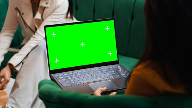 Hotel guest using laptop with greenscreen layout in lobby