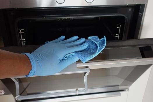 hand in gloves Cleaning the kitchen oven.