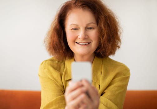 Closeup shot of smiling senior woman using her smartphone at home