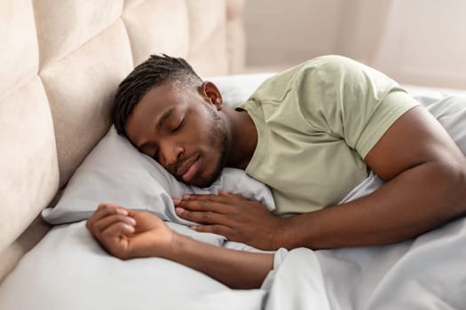 Sleeping black guy enjoying peaceful restful nap lying in bed