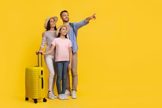 Family Travel Concept. Happy parents with daughter carrying suitcase and pointing aside