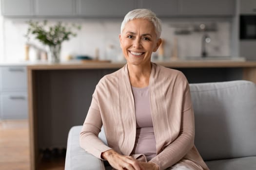 Relaxed and joyful senior woman sitting on sofa at home