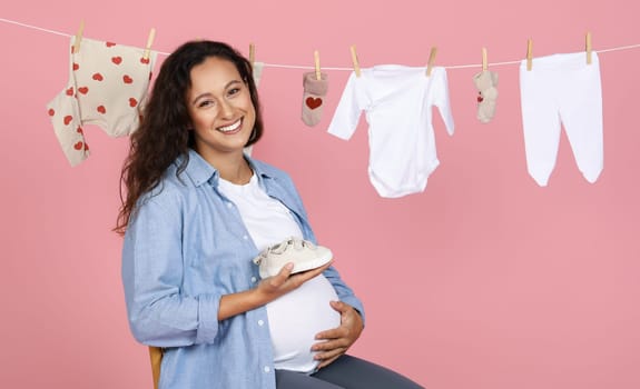 Smiling expecting woman with baby shoe, clothesline