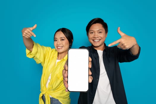 Enthusiastic woman and man pointing with excitement to a smartphone with a blank screen
