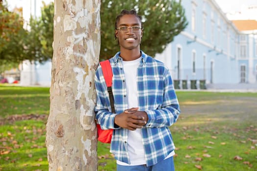 Confident African American young man student with backpack stands outdoor