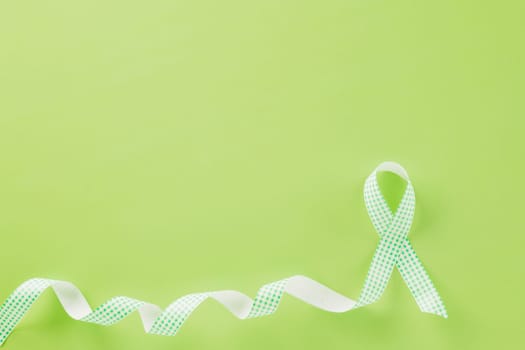 Green awareness ribbon of Gallbladder and Bile Duct Cancer month isolated on green background with copy space, concept of medical and health care support