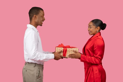Loving black man giving present to pleased woman, side profile