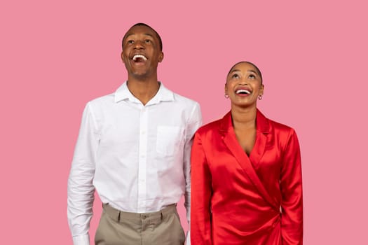 Laughing black couple in white and red looking up at free space