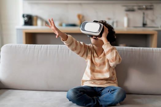 Excited black little boy wearing virtual reality headset having fun at home