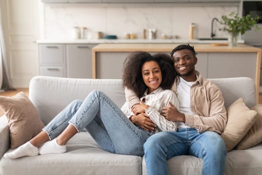 Romantic African Couple Hugging While Chilling On Couch At Home