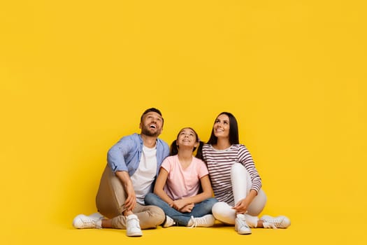 Nice Promo. Caucasian Family Of Three Sitting On The Floor, Looking Up