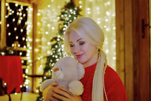Woman by Christmas tree. Festive setting. Illustrating holiday cheer and celebration. She is posing for a picture, and there are presents nearby, adding to the festive atmosphere.