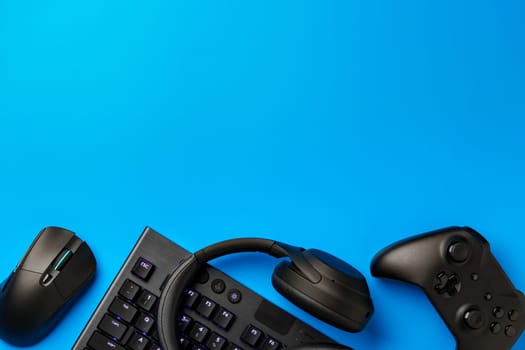 Computer keyboard and joystick on blue background top view