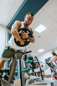 Man bodybuilder in white shirt training in a gym