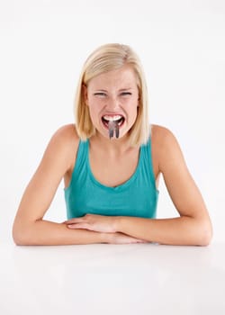 Crazy, woman and portrait of eating fish, tail or strange food in mouth on white background of studio. Dislike, diet and person with weird seafood, cuisine and disgust for taste of tuna or salmon