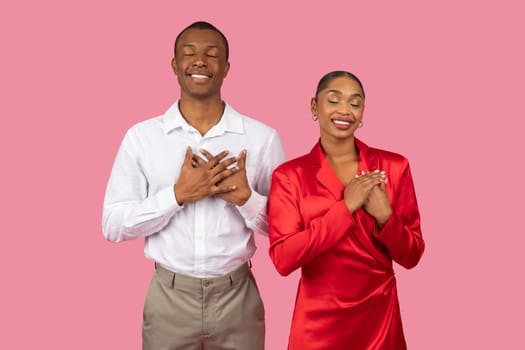 Content black couple with hands on heart, eyes closed