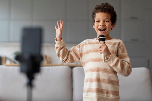 Domestic Concert. Cheerful black little boy singing and recording video at home