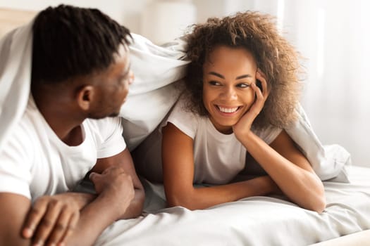 Happy Young Black Lovers Couple Flirting In Bed Under Blanket