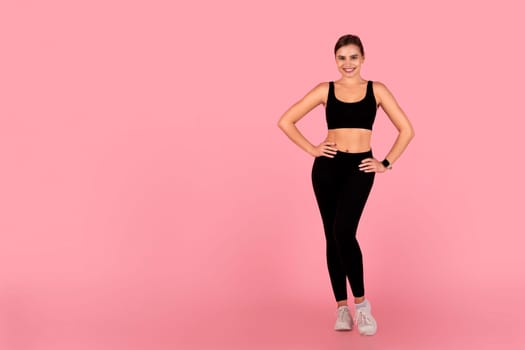 Confident young woman posing in sportswear on pink studio background