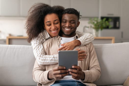 Cheerful African American Couple Using Digital Tablet Browsing Internet Indoor