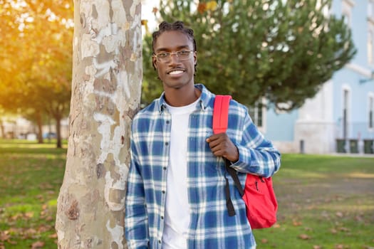 Portrait of successful black student guy wearing glasses posing outdoor