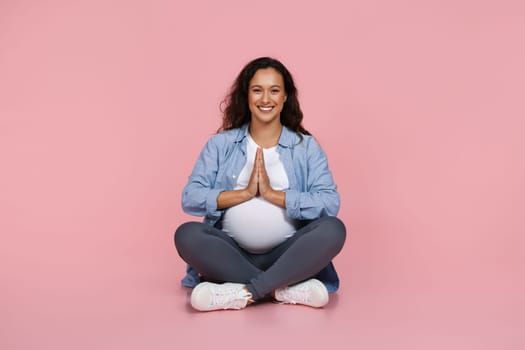 Peaceful pregnant woman meditating on pink background