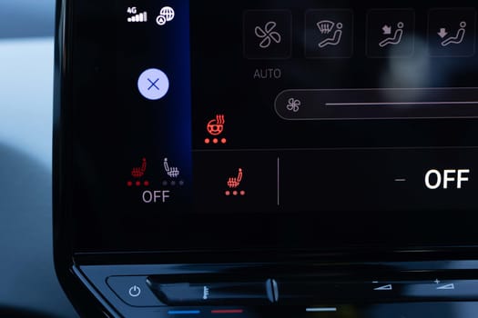 Switching ON heated seats of car by pressing the buttons. Heated seat dashboard in a car. Steering wheel heating button in the car. Electric car control panel with steering wheel and seat heating