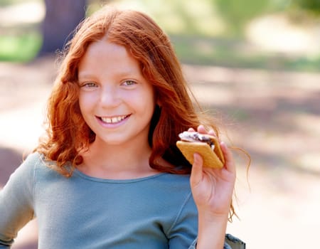 Young girl, camping and smores in portrait in nature, happiness and hungry for sweet snack in woods. Red hair, child and happy face by sugar candy for eating, relax and outdoor on holiday adventure