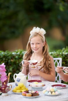 Girl, kid and portrait in garden with tea party for birthday, celebration and playing outdoor with cake. Person, child and face with happiness in backyard of home or house with cup or flower in hair.
