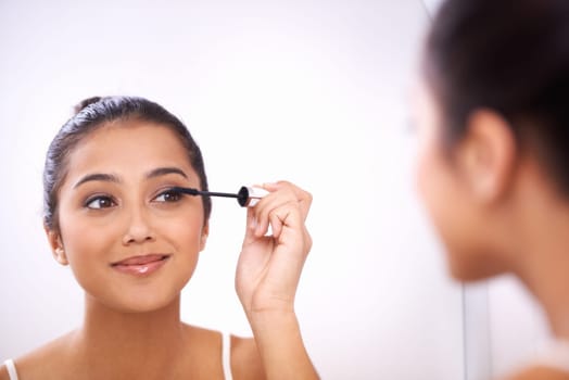 Woman, mascara wand and beauty in mirror, skincare and application of cosmetics for grooming. Female person, dermatology and transformation in bathroom, eyelash and brush or tool for makeup product