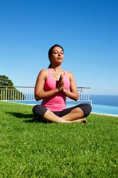 Meditation, yoga and woman on grass praying for holistic balance, mindfulness and breathing exercise. Meditating, hands in prayer and person by ocean for wellness, health and zen energy outdoors