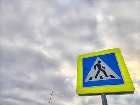 Pedestrian crossing sign on the background of a gray sky with clouds. Drawing, pictogram for pedestrians crossing the road