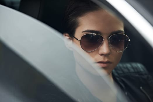 Window, car and face of woman with sunglasses for cool style and accessory while driving on a trip. Edgy, trendy and eyewear with a fashionable female person in a transport vehicle for journey