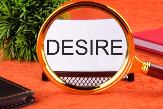 Desire text concept. DESIRE word, text written on a business card through a magnifying glass on an orange background