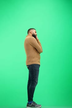 A man, full-length, on a green background, is bored