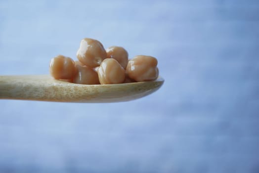 chick peas on a wooden spoon on white background