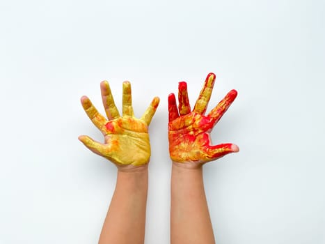 Childrens hands painted with yellow and red paint on white background.