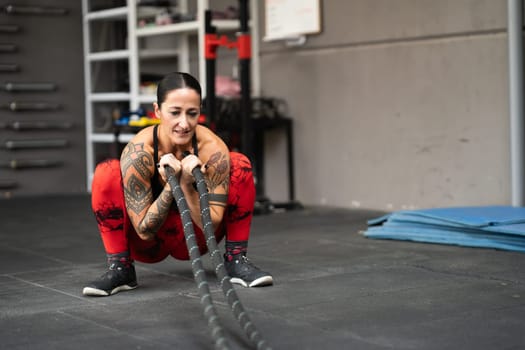 Woman using a battle rope to work out in a gym