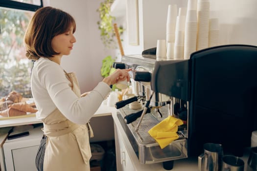 Professional female barista making coffee in a coffee machine while working in cafe
