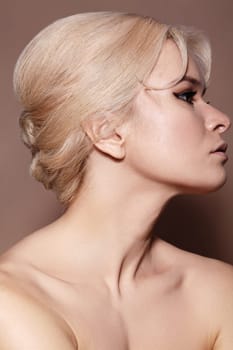 Sexy model with retro make-up, clean skin, blond hair on beige background. Elegant woman with fashion makeup, hairstyle
